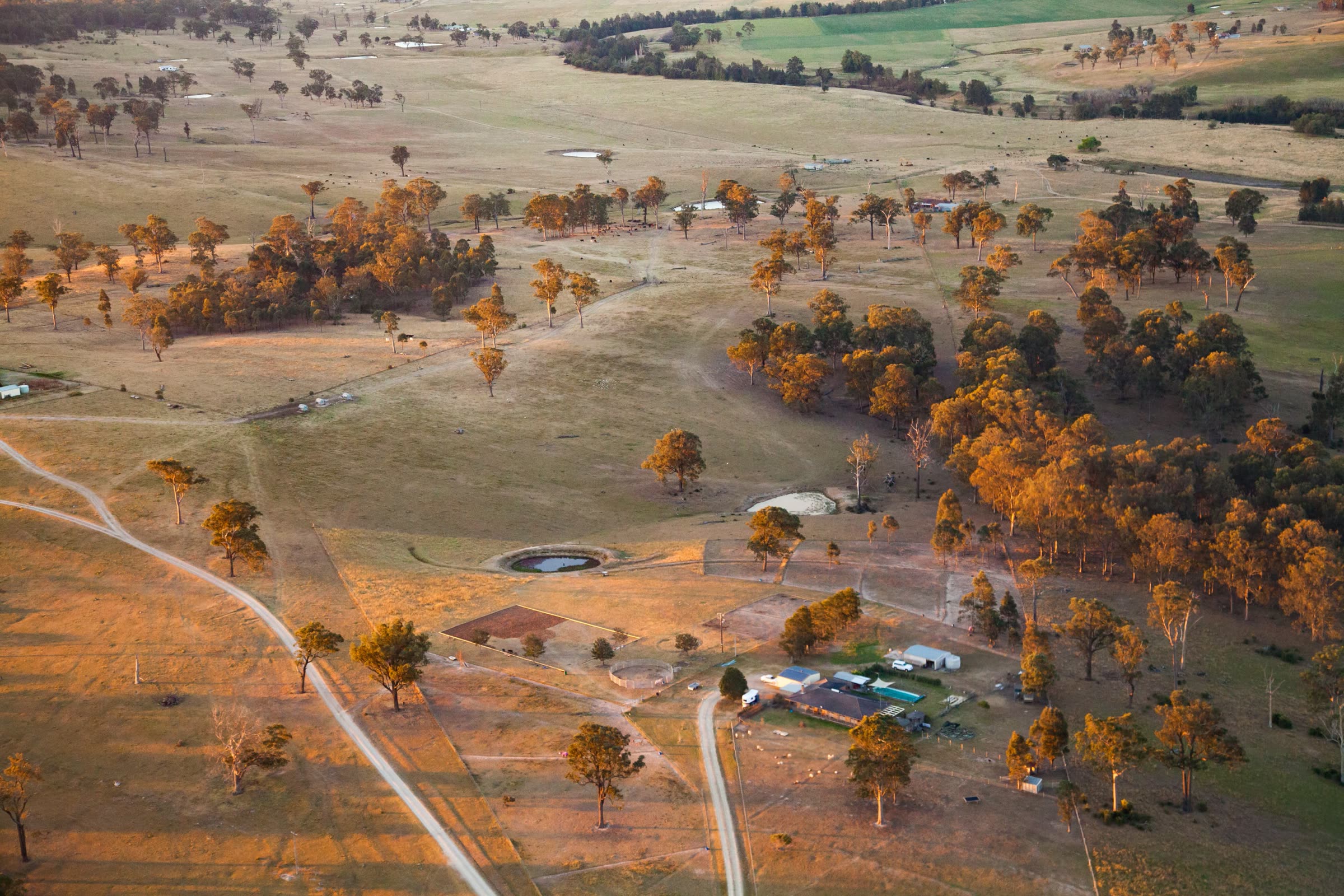 Aerial view of grazing country near Elderslie, New South Wales, with a homestead, dam and tracks among scattered trees